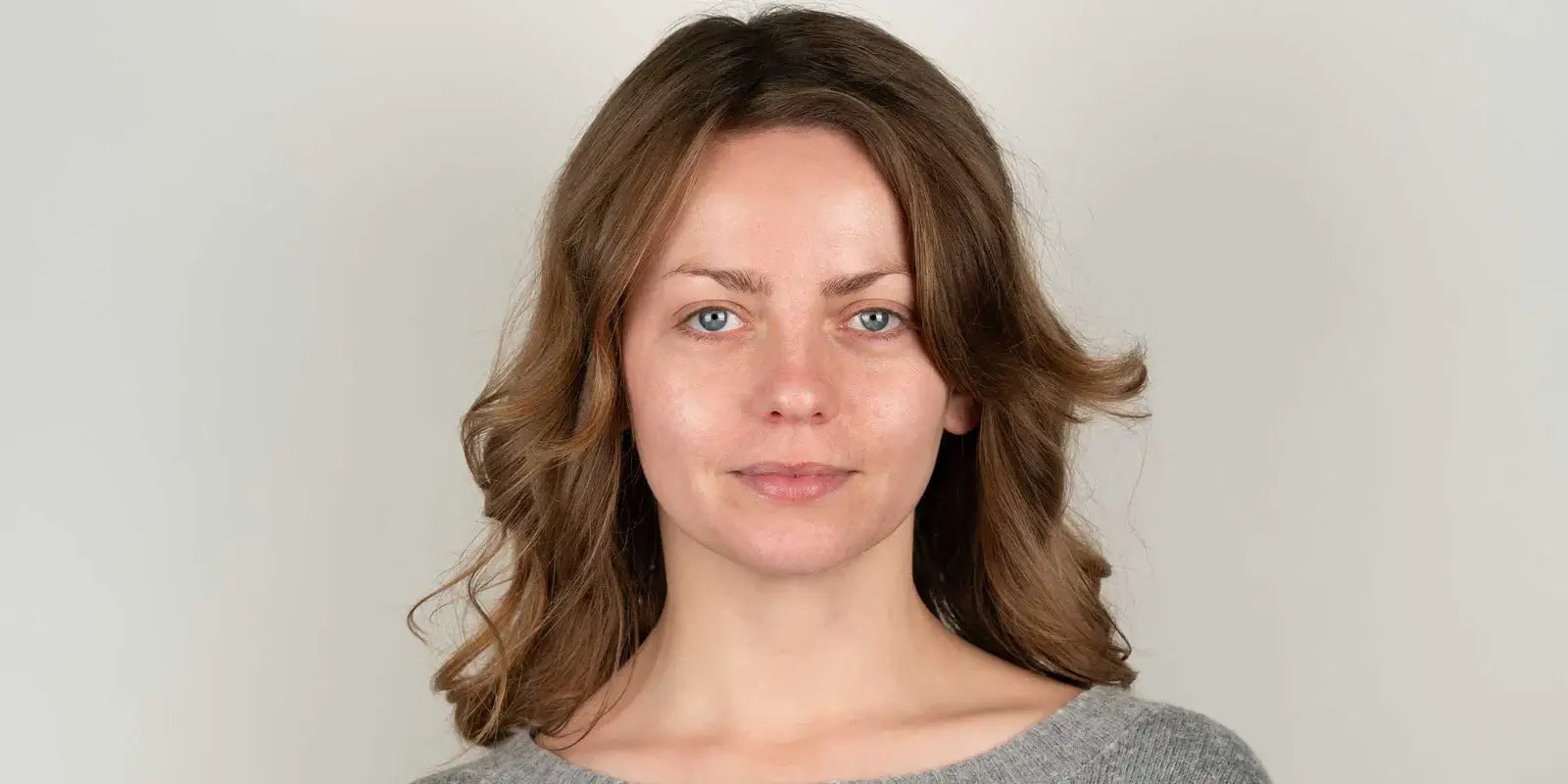 A woman in a gray sweater is posing for a photo.