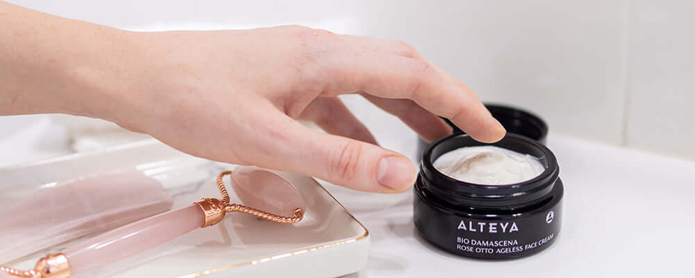 A hand reaching into a jar of veela face cream.