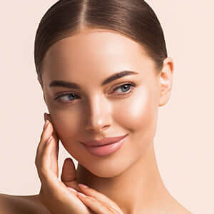 A woman posing with her hands on her face.
