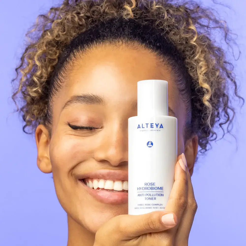 A woman holding up a bottle of Rose Hydrobiome Anti-Pollution Toner.