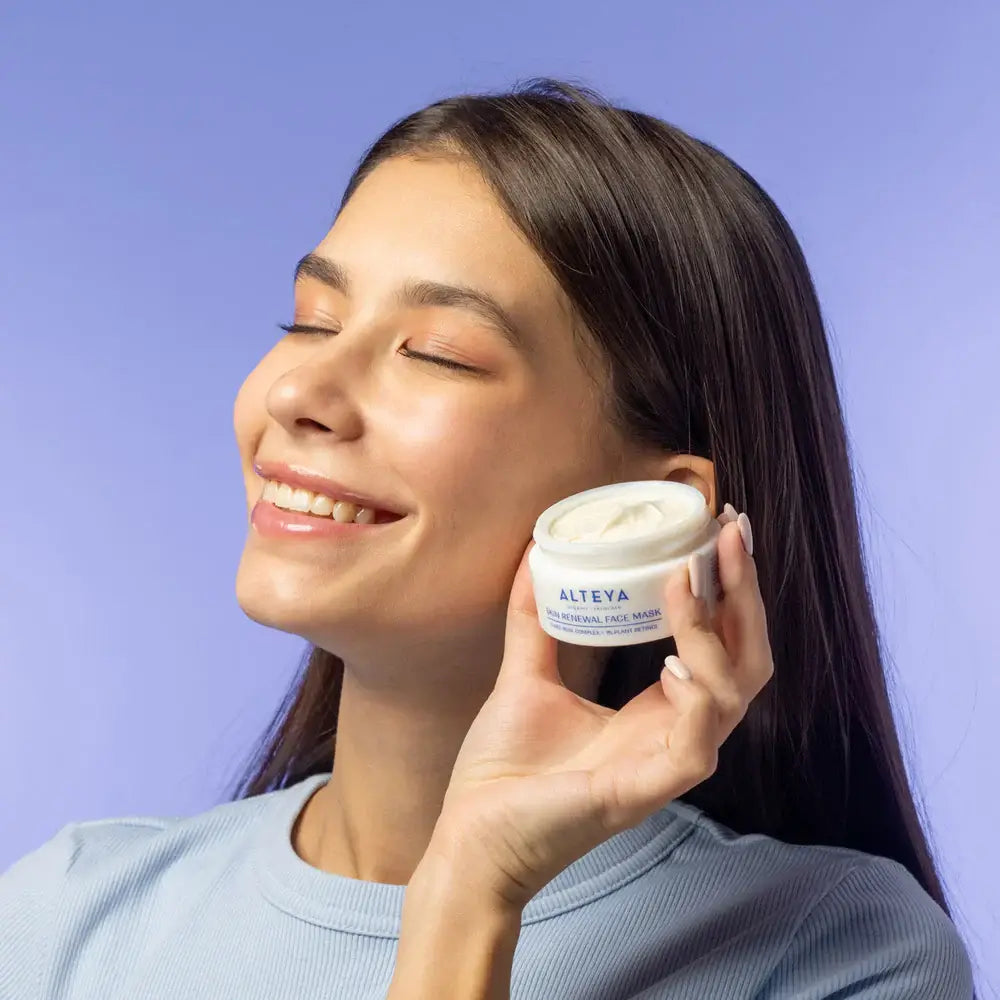 The woman is holding a jar of Rose Hydrobiome Skin Renewal Face Mask in her hands.