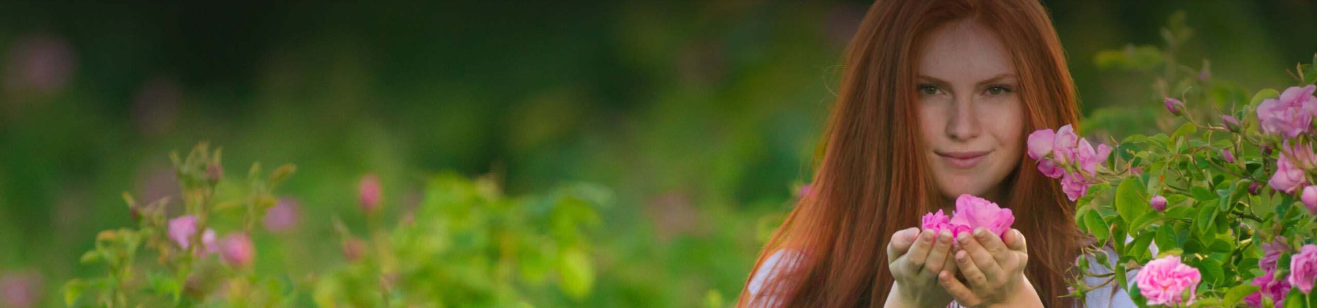 A woman with red hair is surrounded by pink flowers.