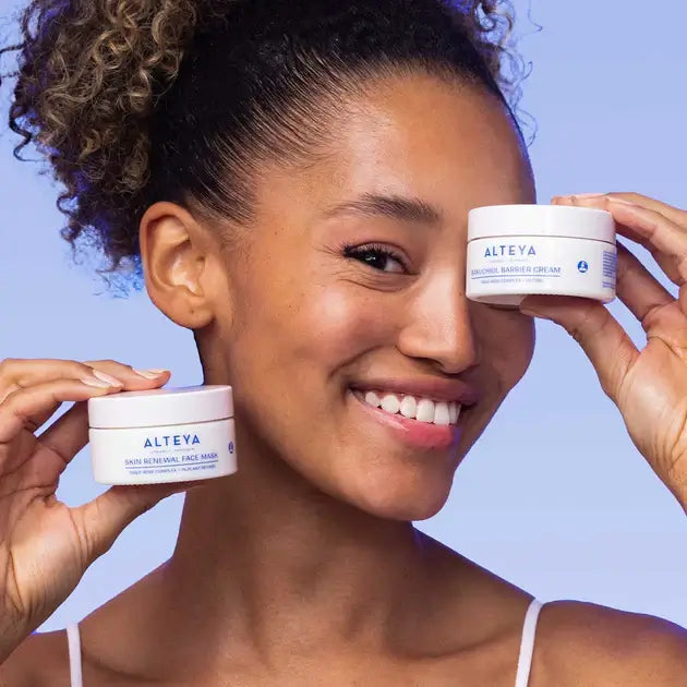 A woman is holding up two jars of face cream.