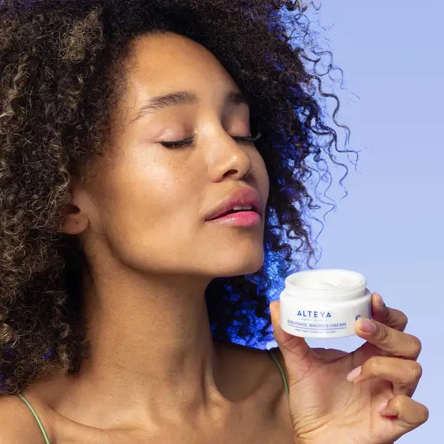 A woman with curly hair holding a jar of cream.