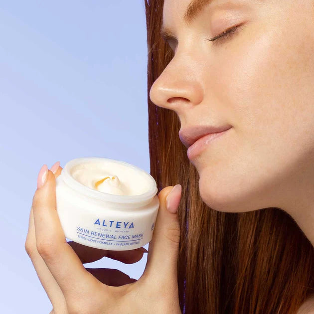 A woman is holding a jar of cream in her hand.