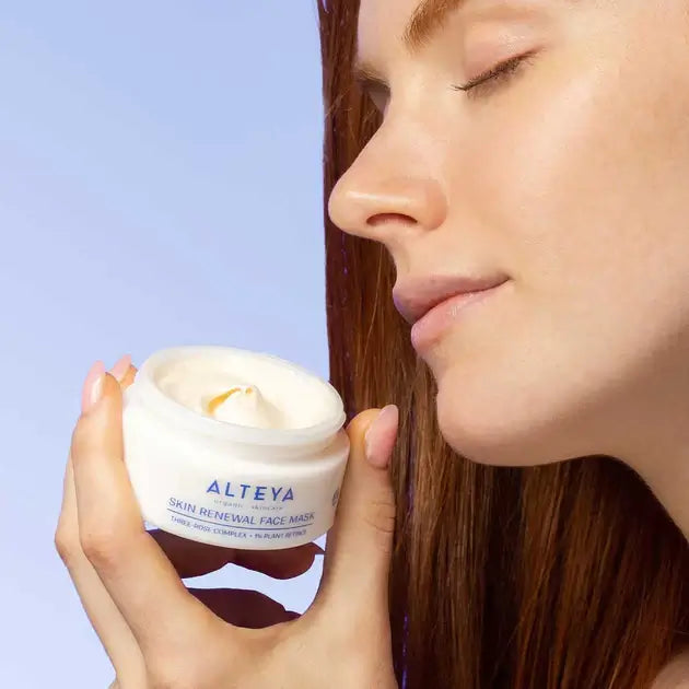 A woman is holding a jar of cream in her hand.