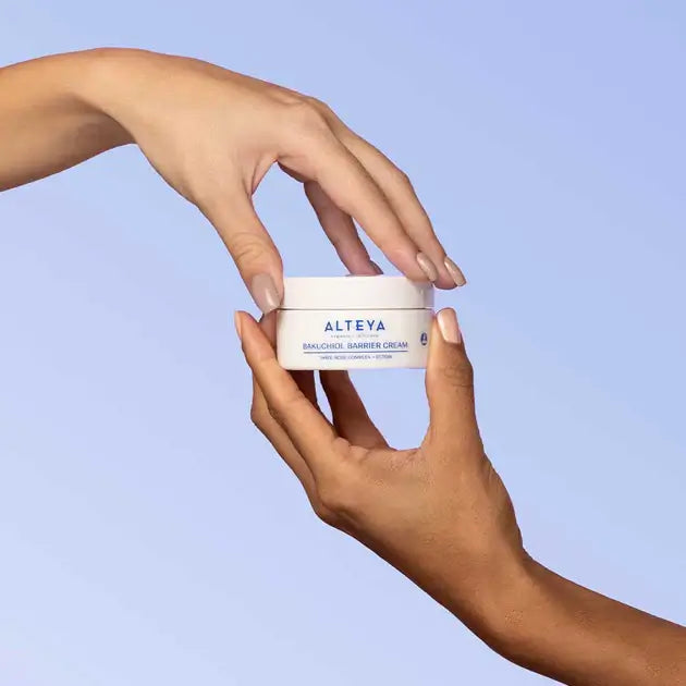 Two hands holding a jar of a cream.