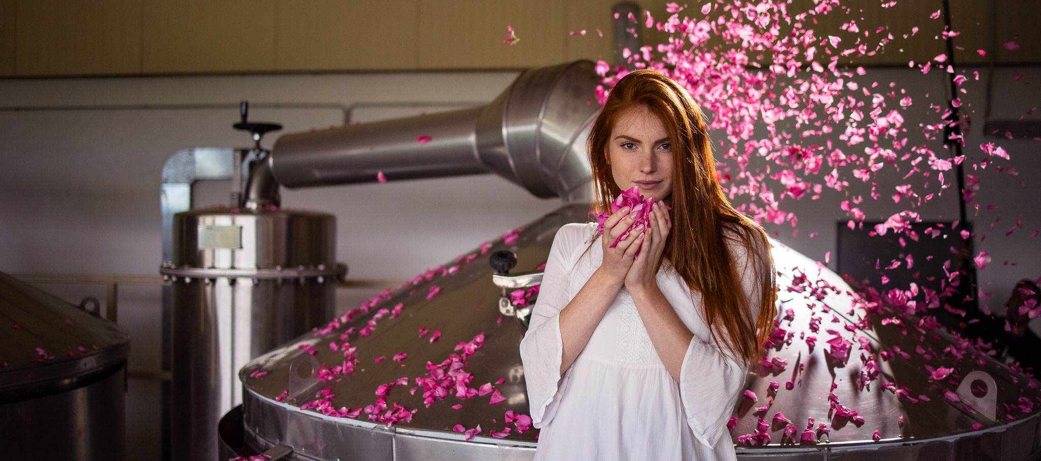 A woman posing in front of a pink flower factory.