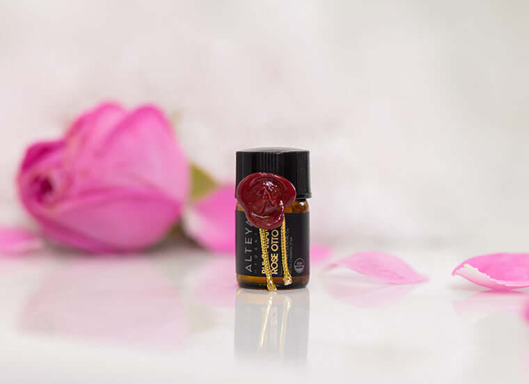 A small bottle of rose essential oil on a white surface.