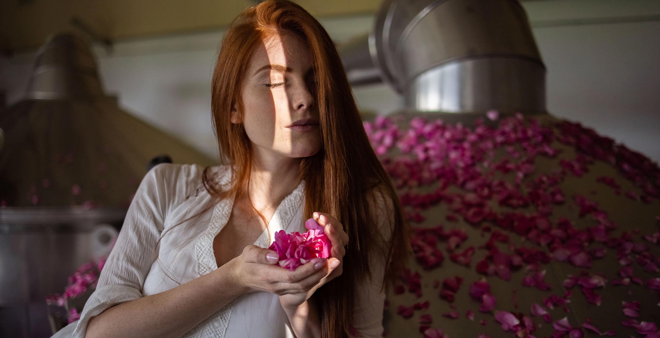 A woman is smelling rose petals in a brewery.