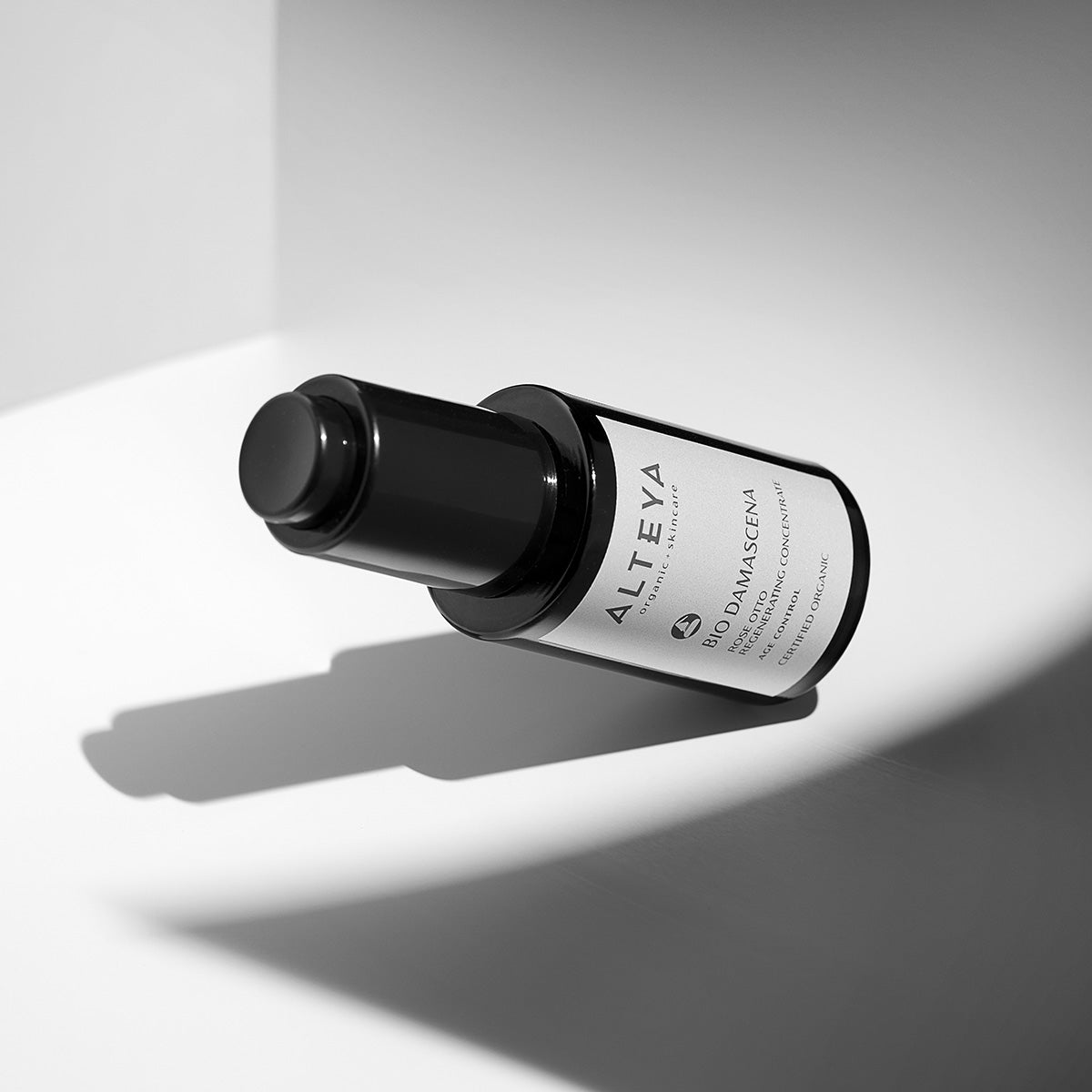 An Alteya Organics Bio Damascena Rose Otto Regenerating Concentrate, known for its regenerating concentrate properties, elegantly placed on a pristine white surface.