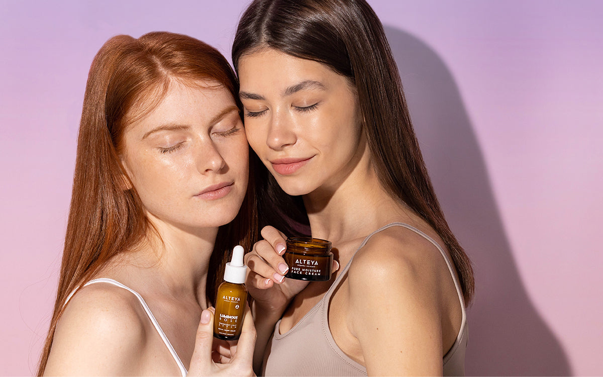 Two women holding a bottle of skin care products.