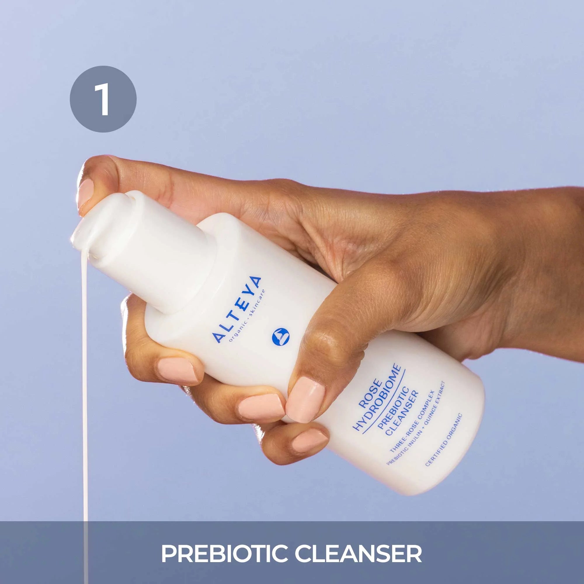 A hand holding a bottle of prebiotic cleanser.