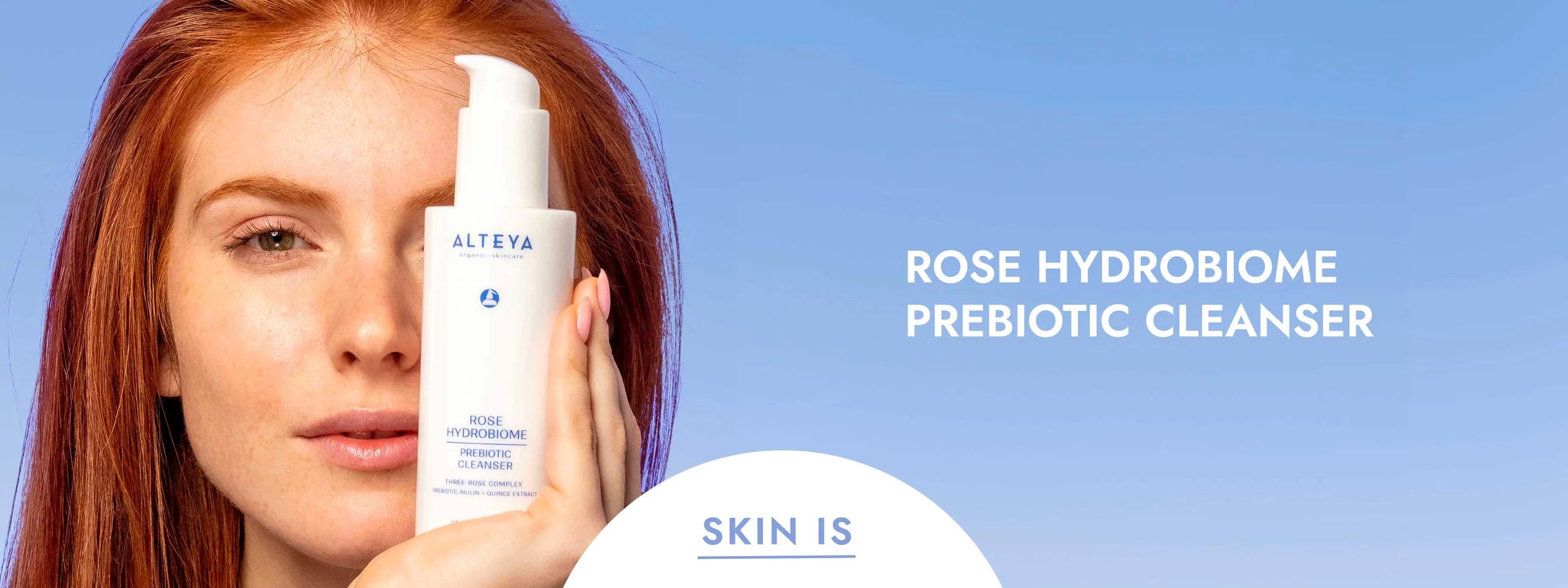 A woman is holding up a bottle of rose hydrome prebiotic cleanser.