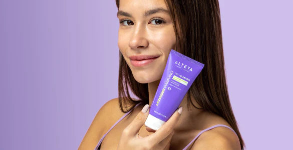 A woman is holding a tube of purple cream.