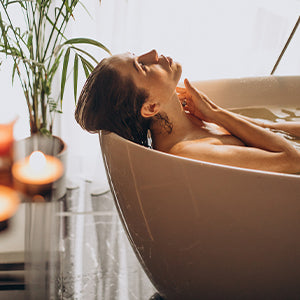 A woman relaxing in a bathtub with candles.