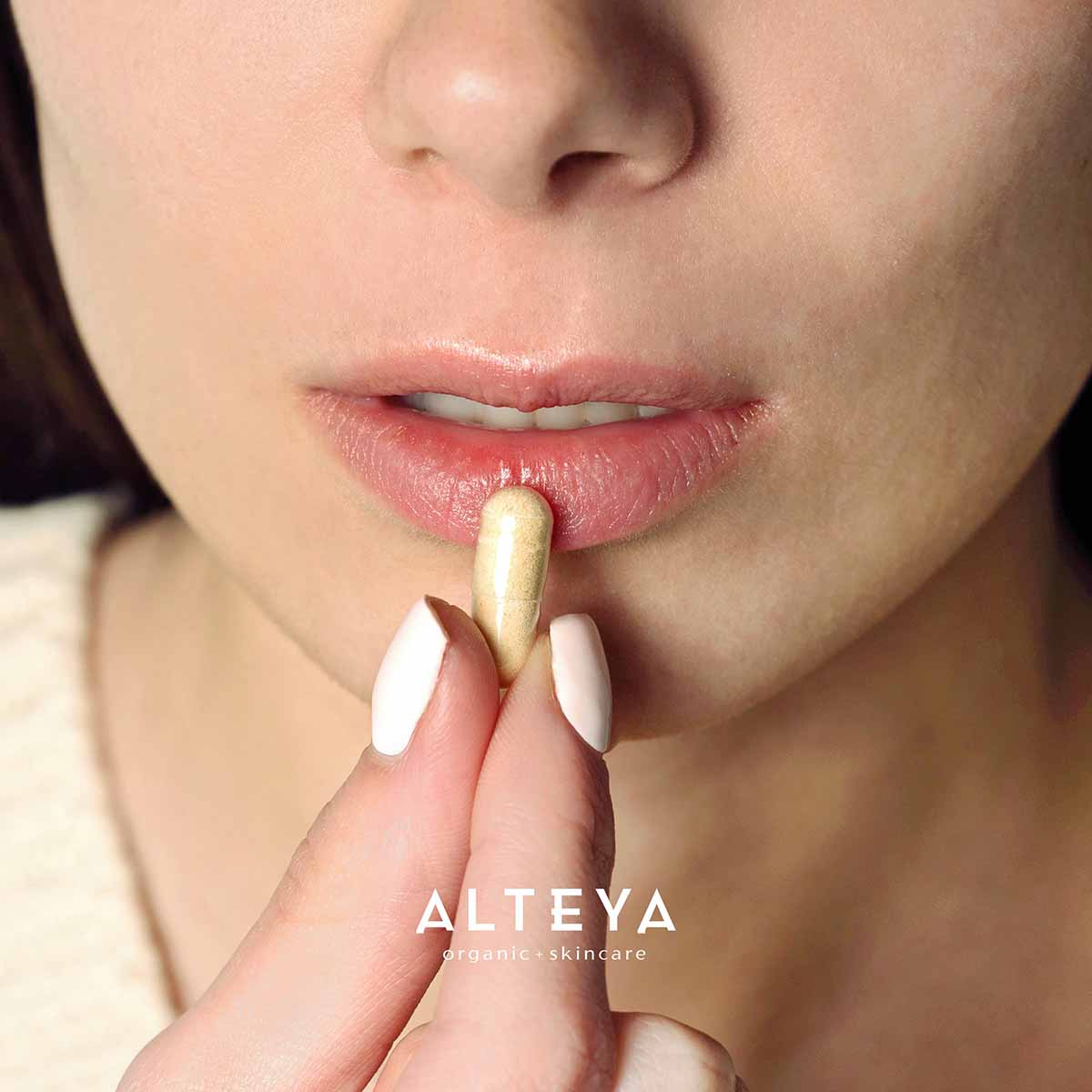 A woman is holding Alteya Organics' Rose Beauty Prebiotic and Probiotic - Synbiotic Skin & Metabolism Vegan Organic Supplement in her mouth, promoting gut health.