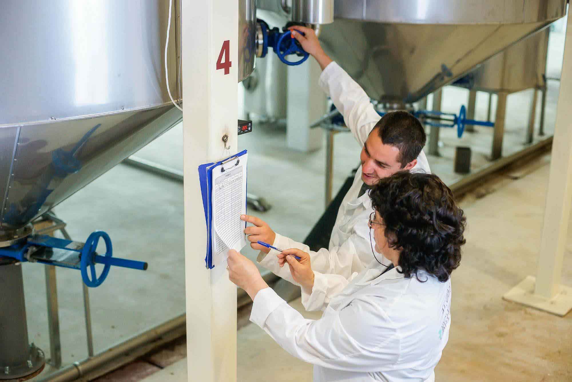 Two people in lab coats looking at a clipboard.