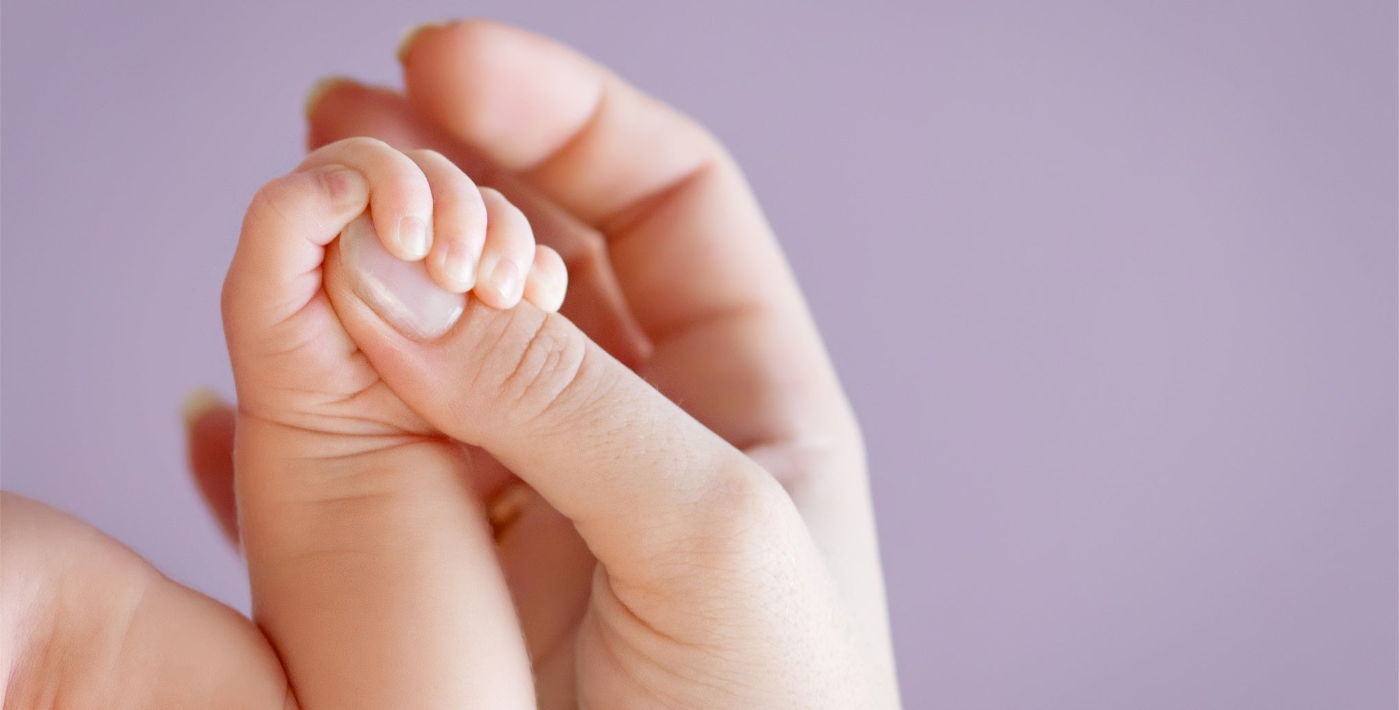 A woman's hand holding a baby's foot.