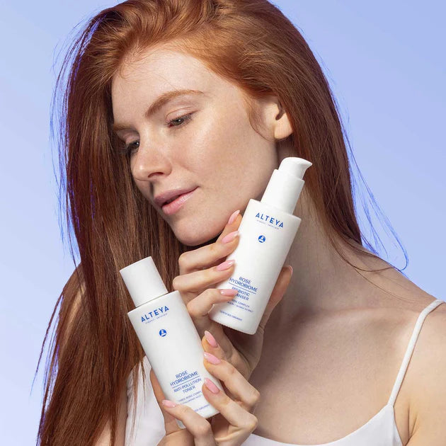 A woman holding two bottles of skin care products.